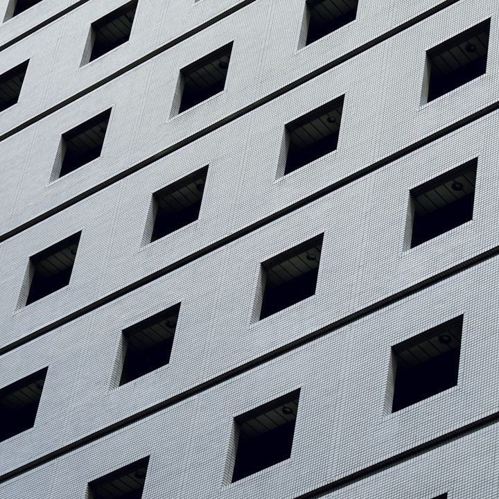 Repeating grid of recessed windows across a pale building facade